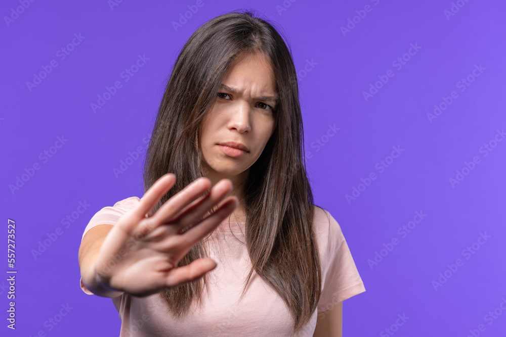Uninterested teen girl disapproving with NO hand sign gesture. Denying, rejecting, disagree. Portrait of young woman on violet background, timeout concept. Uninterested teen girl disapproving with NO hand sign gesture. Denying, rejecting, disagree. Portrait of young woman on violet background, timeout concept.