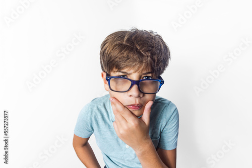 An exagerated close-up portrait of a funny little boy with glasses making a thinking face on a solid white background taken with a fish eye lens