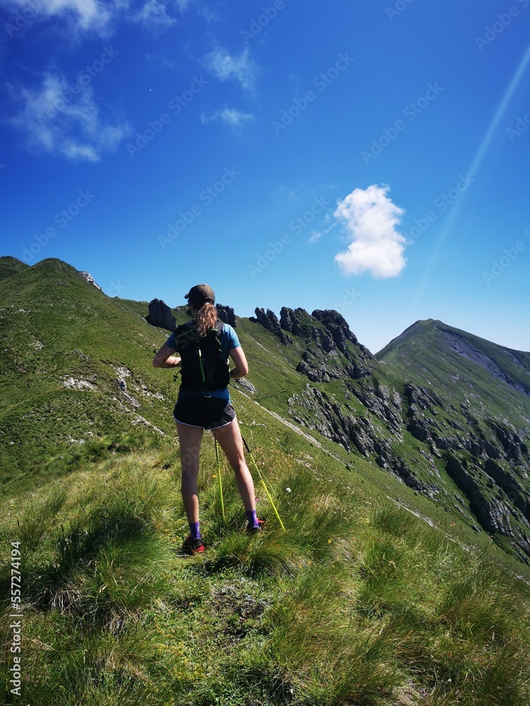 Wandernde Frau steht am Berggipfel und genießt die Aussicht
