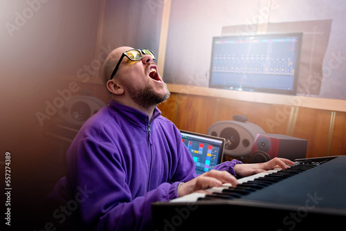 Male musician emotionally plays midi keyboard in recording studio. Music production