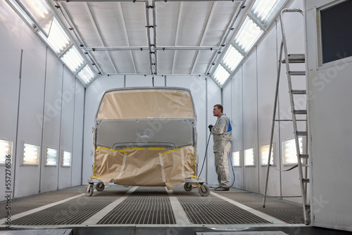 Horizontal long shot of car painter standing next to truck prepared for painting