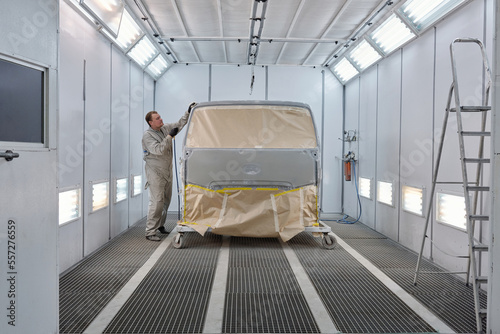 Horizontal side view long shot of car painter doing preparatory work for vehicle painting