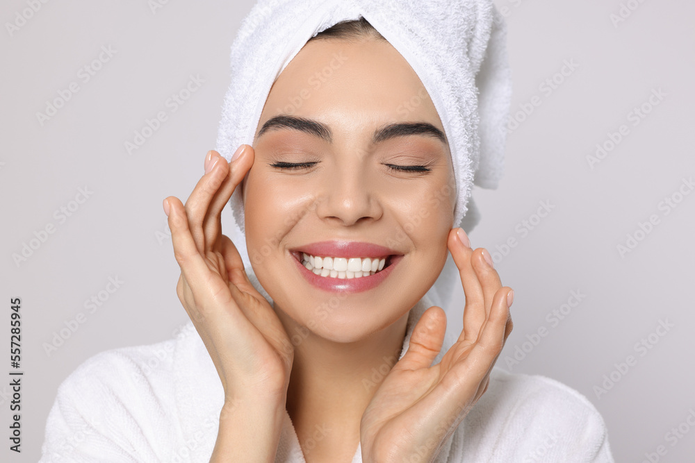 Young woman in bathrobe with towel on light grey background. Spa treatment Young woman in bathrobe with towel on light grey background. Spa treatment