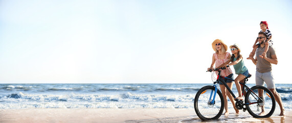 Happy family with bicycle on sandy beach near sea, space for text. Banner design