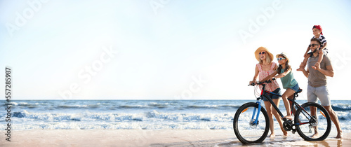 Canvas Print Happy family with bicycle on sandy beach near sea, space for text