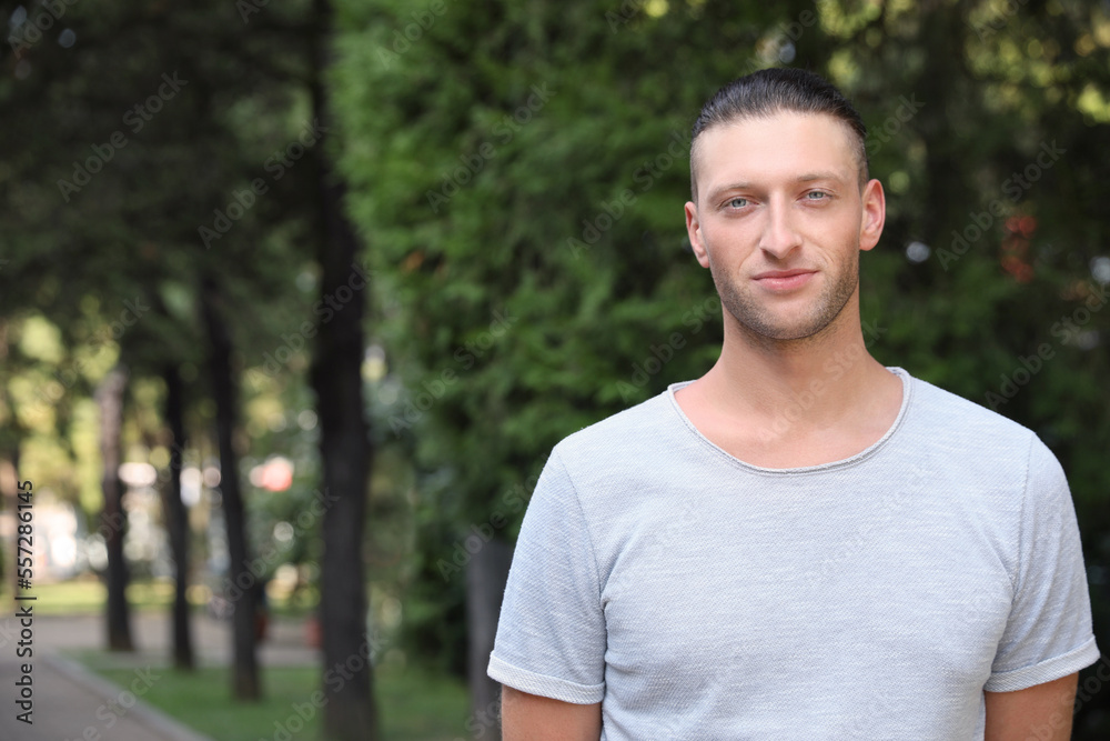 Portrait of handsome young man in park, space for text