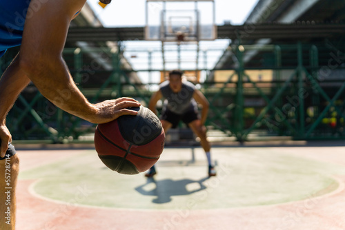 Two man athlete playing streetball match shooting and defense basketball on outdoors court together in sunny day. Sportsman do sport training basketball at street court under highway in the city. © CandyRetriever 