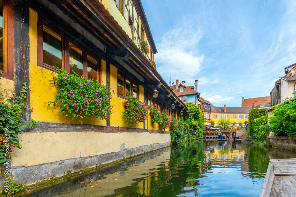 View of half timber homes and cafes from a boat on the Lauch canal in the historic medieval Petite Venice district of Colmar, France, in the Alsace region.	