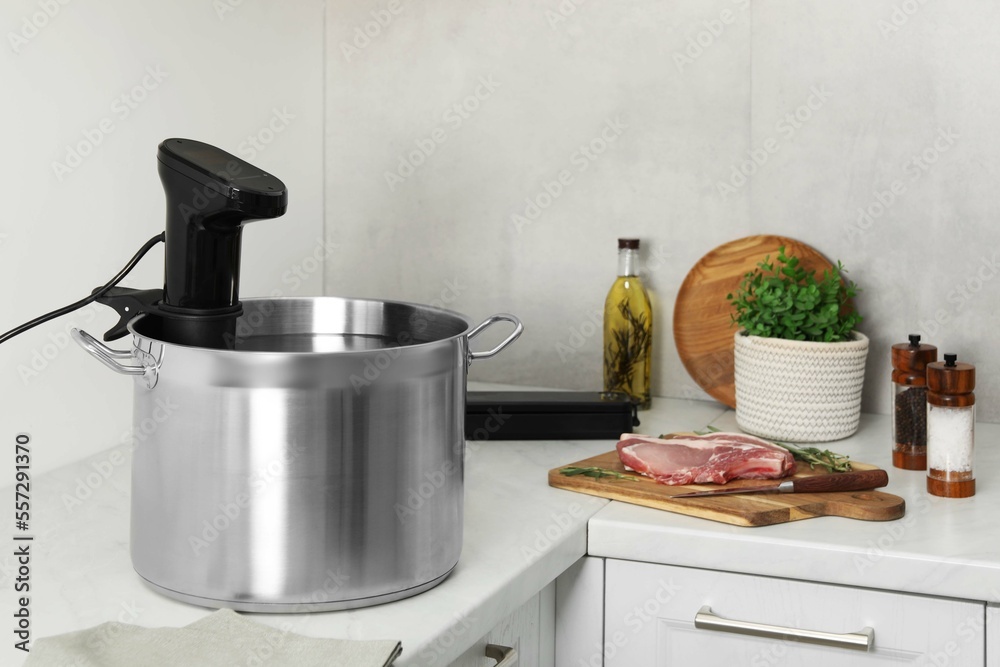 Sous vide cooker in pot and ingredients on white countertop. Thermal immersion circulator Sous vide cooker in pot and ingredients on white countertop. Thermal immersion circulator