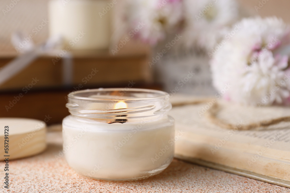 Burning candle and book on beige textured table Burning candle and book on beige textured table