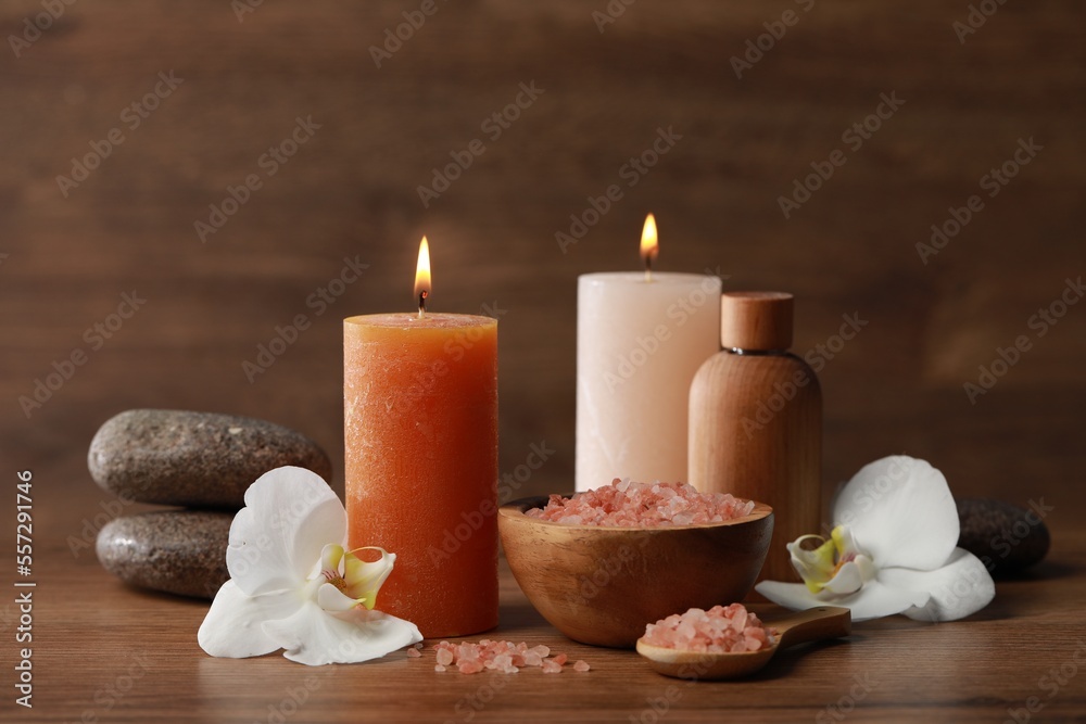 Beautiful spa composition with sea salt, burning candles and flowers on wooden table Beautiful spa composition with sea salt, burning candles and flowers on wooden table