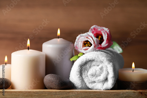 Beautiful composition with spa stones, flowers and burning candles on wooden table