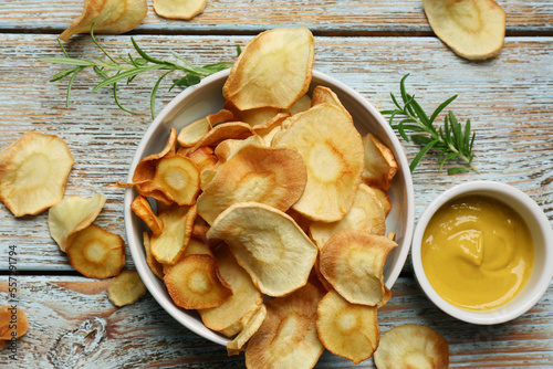 Tasty homemade parsnip chips with sauce and rosemary on old light blue wooden table, flat lay © New Africa