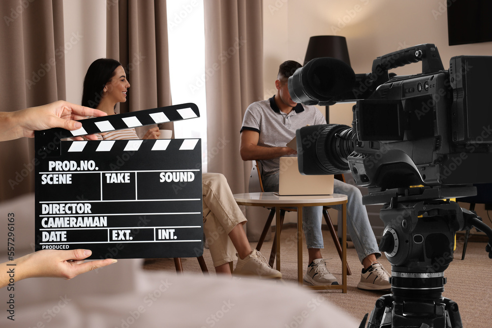 Shooting movie. Second assistant camera holding clapperboard near video  camera in front of couple (actors) at hotel (film set) Stock Photo | Adobe  Stock