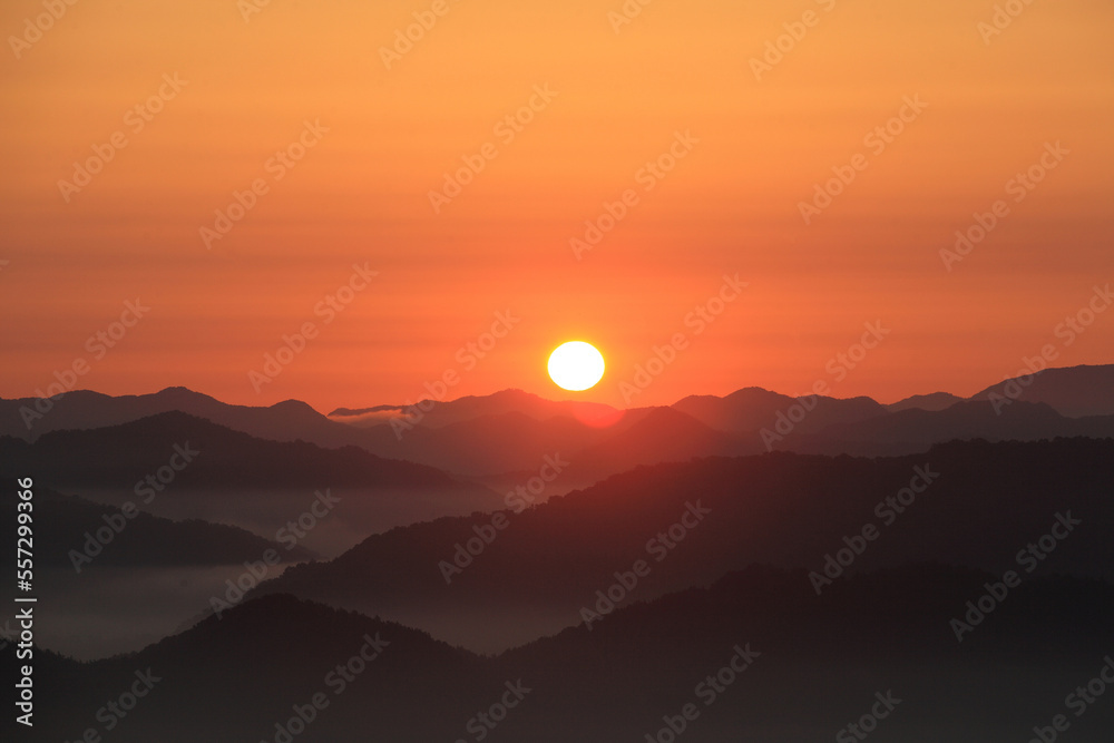 붉은 하늘의 산 위로 아름다운 태양이 밝게 떠오른다.