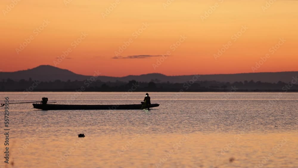 asian fishermen on boat looking for fish in Lake with morning sky asian fishermen on boat looking for fish in Lake with morning sky