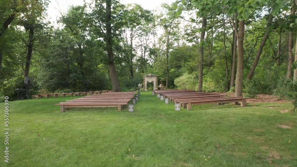 Smooth gimbal entering empty outdoor forest wedding ceremony arrangement with wooden chairs Smooth gimbal entering empty outdoor forest wedding ceremony arrangement with wooden chairs