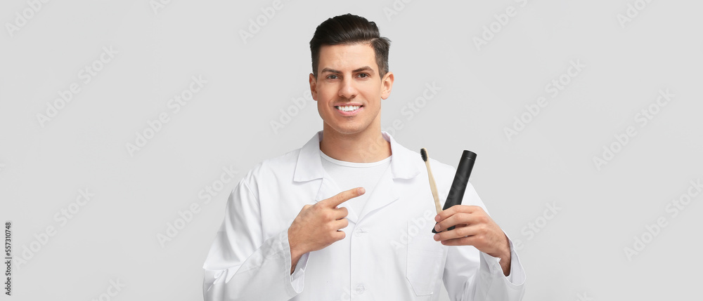 Handsome young man with activated charcoal tooth paste and brush on light background Handsome young man with activated charcoal tooth paste and brush on light background