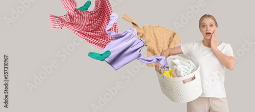 Shocked young woman with flying clothes and basket on grey background. Banner for design