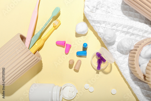 Different earplugs, pills and bath supplies on color background