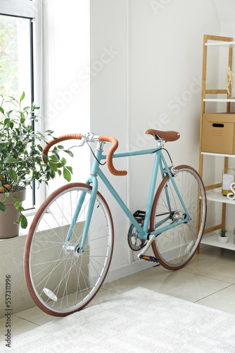 Stylish bicycle near light wall in living room