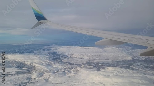 View from airplane window flying over winter Alaska landscape.