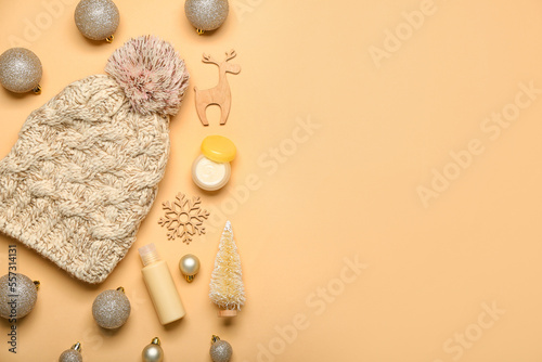 Composition with cosmetic products, Christmas decorations and warm hat on color background