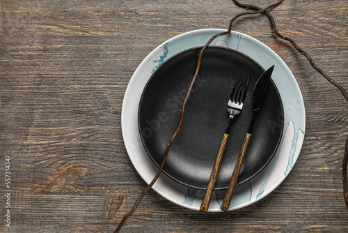 Black plate with cutlery on wooden background
