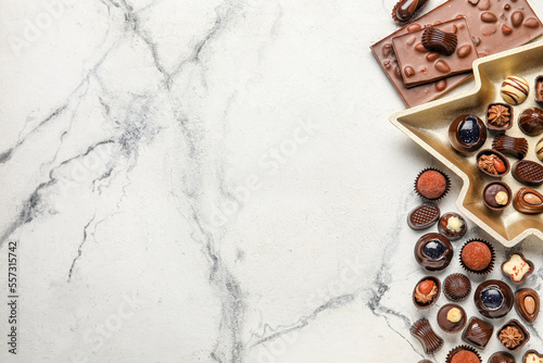 Candies and chocolate bar on white marble background