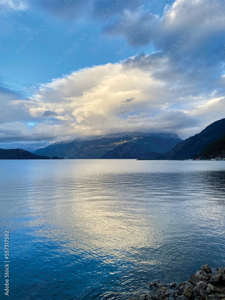 A sunny winter afternoon in Harrison Hot Springs, British Columbia, Canada. Blue sky, white cloudy, and beautiful reflection. Some waves and thin ice on the lake surface. A sunny winter afternoon in Harrison Hot Springs, British Columbia, Canada. Blue sky, white cloudy, and beautiful reflection. Some waves and thin ice on the lake surface.