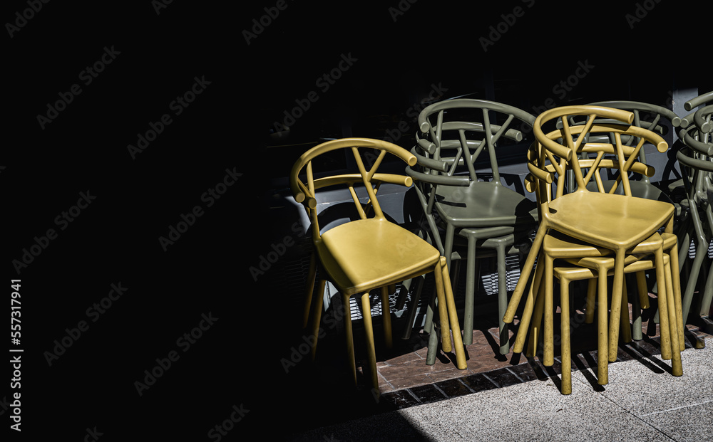 Detail of Stack of Dark green (Khaki color) and Yellow plastic chairs.