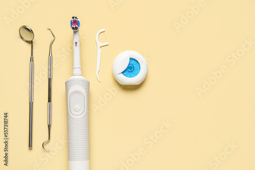 Dental tools with electric brush, toothpick and floss on yellow background © Pixel-Shot