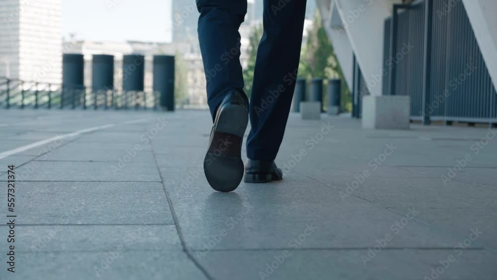Close up legs of business man in leather shoes and classical suit walking confidently around city going to work at office. Rear back view business man walking at downtown. Business and finance concept Close up legs of business man in leather shoes and classical suit walking confidently around city going to work at office. Rear back view business man walking at downtown. Business and finance concept