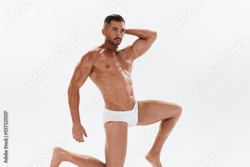 Man athletic body bodybuilder in briefs with naked torso abs full-length in the background  fitness classes. Advertising  sports  active lifestyle  competition  challenge concept.