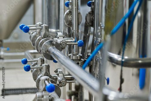 Close-up of metal pipes with blue levers on machinery at manufacturing factory