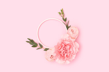 Wreath made of rose, carnation flowers and green eucalyptus branches on a pink background. Floral concept.