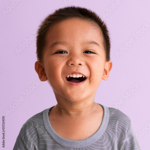 Authentic portrait of a boy, 2 years old asian male toddler, smiles showing his healthy milk teeth and canines. 