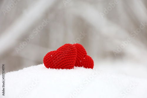 Two love hearts in snow on blurred forest background  Valentine s card. Background for romantic event  Christmas celebration or winter weather