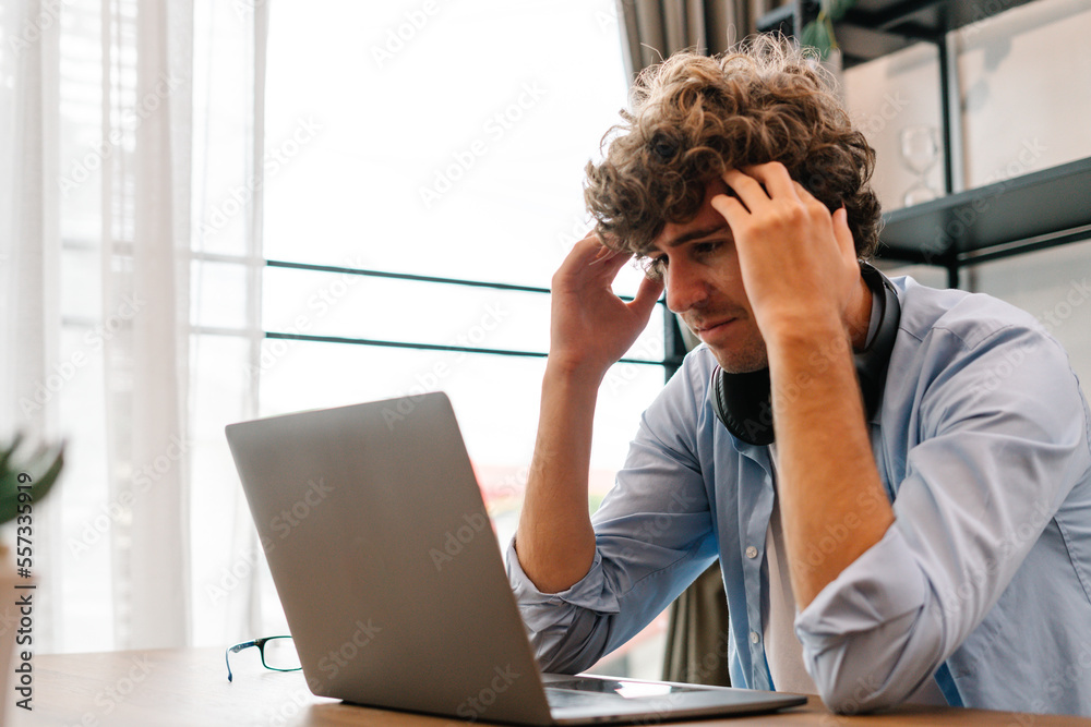 Tired businessman sitting and working with laptop computer, holding head feeling headache Tired businessman sitting and working with laptop computer, holding head feeling headache