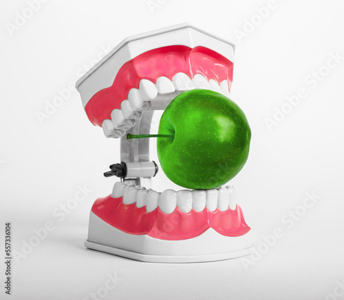 Green apple between teeth, jaws. Eating dangerous poison, fake food concept photo