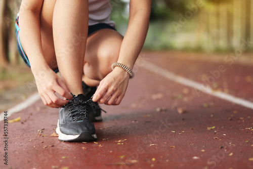 woman tying her shoes on running track. Jogging girl exercise motivation heatlhy fit living.