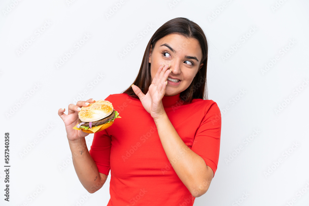 Young caucasian woman holding a burger isolated on white background whispering something Young caucasian woman holding a burger isolated on white background whispering something