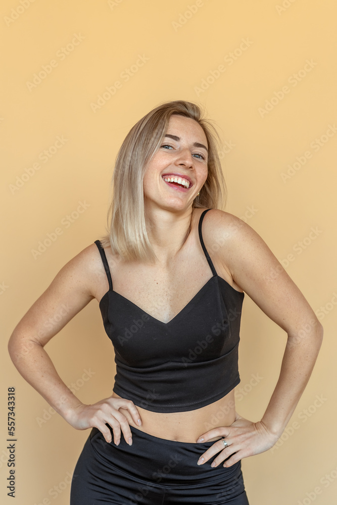 Portrait of smiling young woman with freckles posing in white black clothes over beige background. Young emotional woman Portrait of smiling young woman with freckles posing in white black clothes over beige background. Young emotional woman