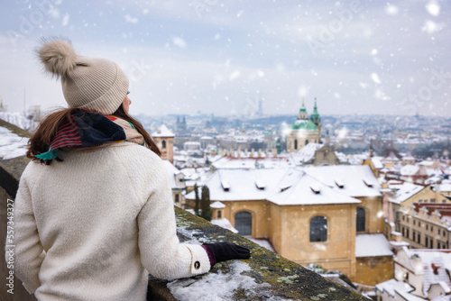 A tourist woman enjoys the panoramic view of the snow covered skyline of Prague, Czech Republic, during a cold winter day