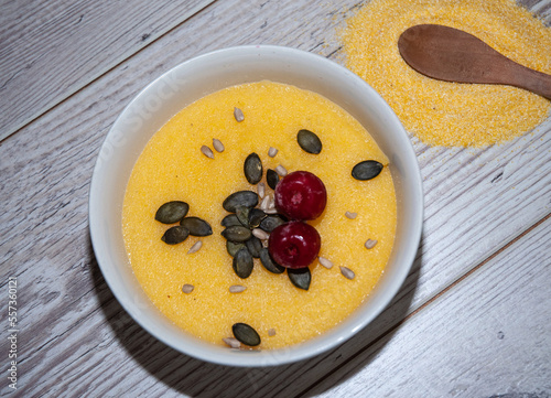 Basic polenta with charry and seeds in a bowl on wooden background.