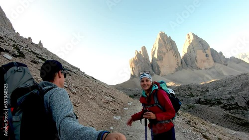 Couple hiking on gravel road enjoying the view on Tre Cime di Lavaredo (Drei Zinnen), mountains in Italian Dolomites, South Tyrol (Alto Adige), Italy, Europe. Desolated raw landscape. Early morning