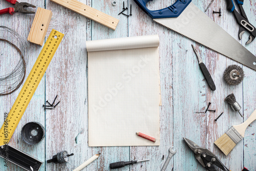 Stół w warsztacie z porozkładanymi narzędziami.  Notatnik na drewnianym stole otoczony narzędziami. © art08