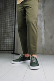 Male legs in pants and green casual sneakers. Men's fashionable shoes