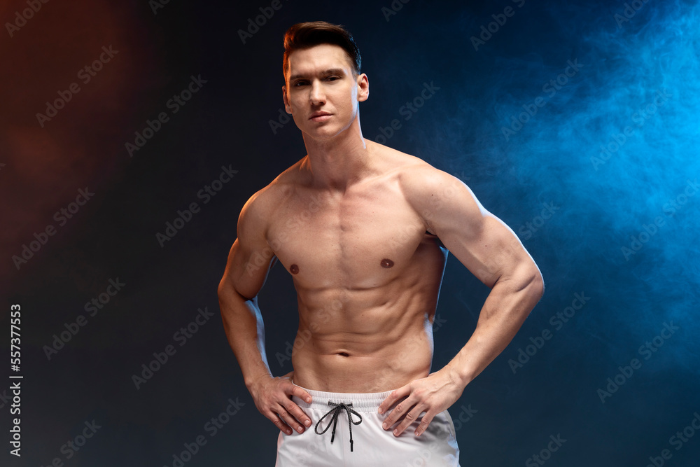 Fototapeta premium Athlete man with beautiful torso isolated on black background with coloured fume