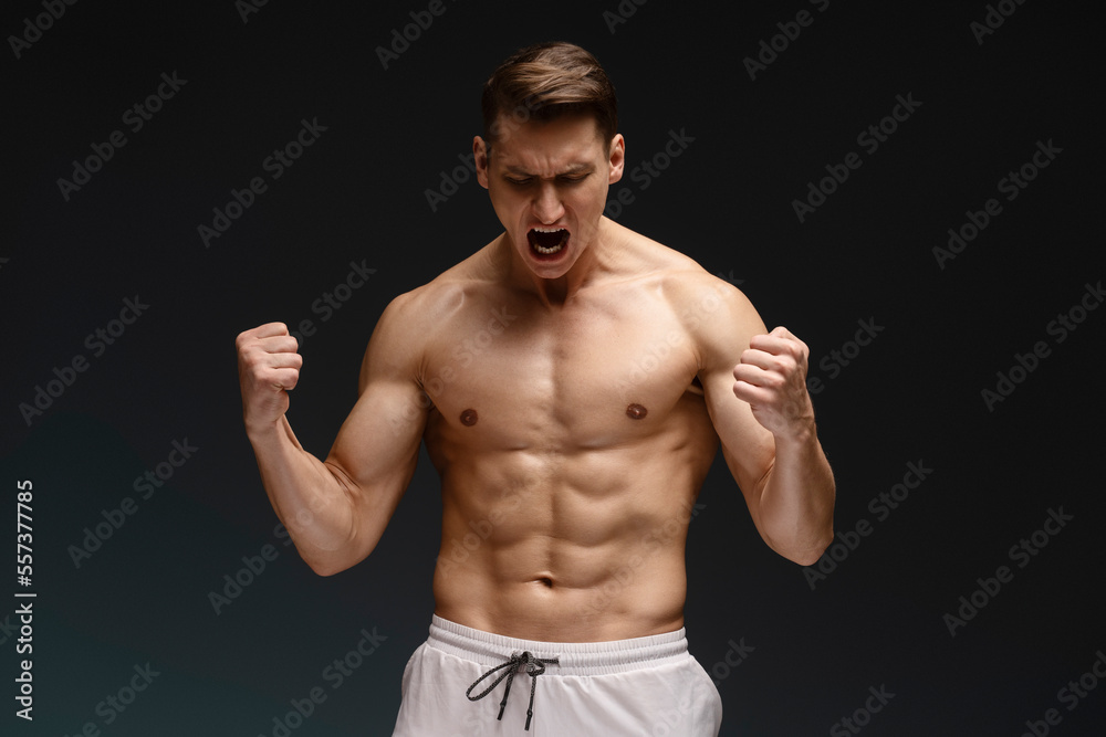 Athletic fitness model screaming and demonstrating muscles while posing